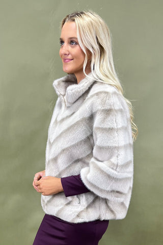 Woman wearing a light gray fur coat against a green background