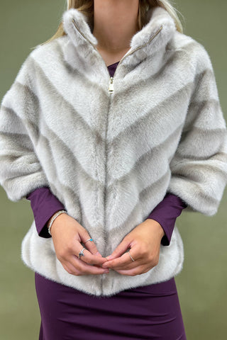 Person wearing a fluffy white jacket over a purple outfit against a green background