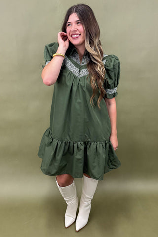 Woman wearing a green dress with white boots against a green background
