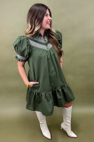 Woman wearing a green dress with white boots against a green background