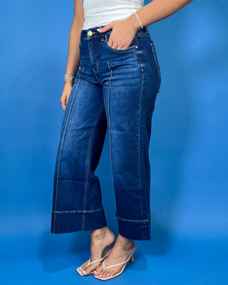 Dark wash high-rise cropped wide leg jeans with statement front seam detailing, subtle fading, and a wide cuffed hem.
