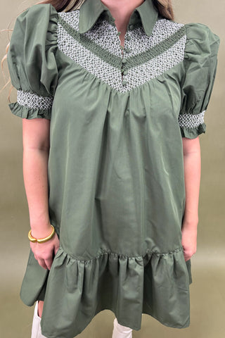 Green dress with white lace details on a plain background