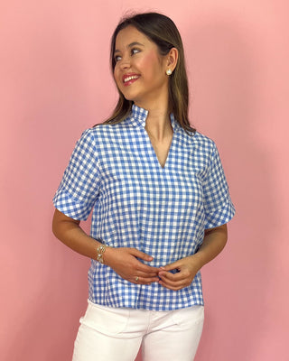 Woman wearing a blue and white checkered shirt against a pink background