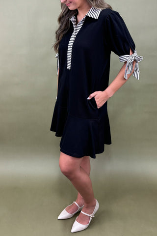 Woman wearing a black dress with striped accents on a green background