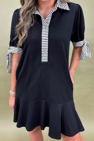 Black dress with striped collar and cuffs on a plain background