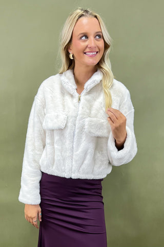 Woman wearing a white fluffy jacket against a green background