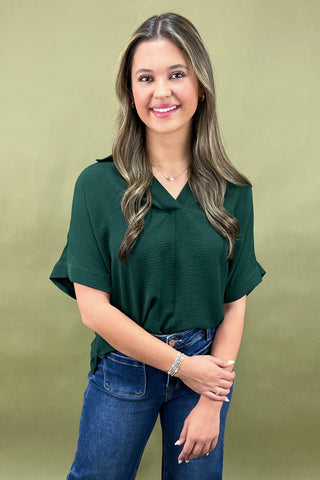 Woman wearing a green top and blue jeans against a green background