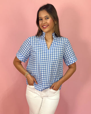 Woman wearing a blue and white checkered shirt against a pink background