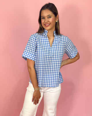 Woman wearing a blue and white checkered shirt against a pink background