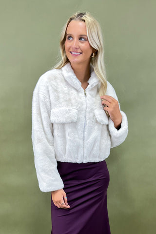 Woman wearing a white fluffy jacket against a green background