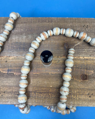 A small clear glass rollerball bottle with a white label and '100% Organic', shown on a wooden surface with a black cap beside it and a blue background.
