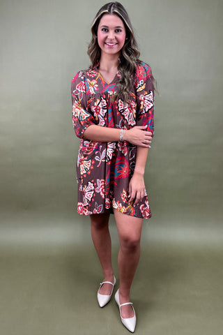 Person wearing a colorful butterfly pattern dress against a green background