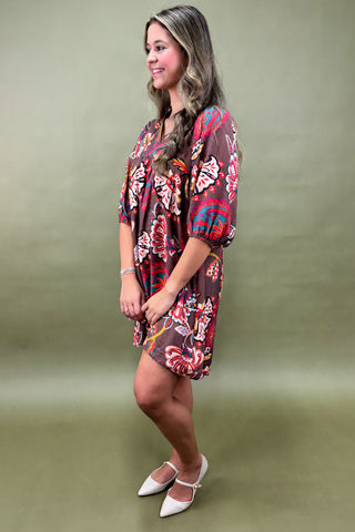 Person wearing a colorful butterfly pattern dress against a green background
