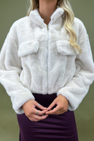 White fluffy jacket worn by a person on a green background