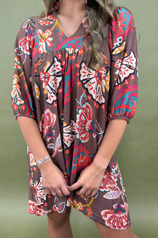 Person wearing a colorful butterfly pattern dress against a green background