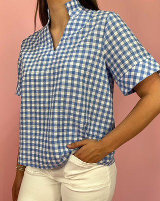 Person wearing a blue and white checkered shirt against a pink background