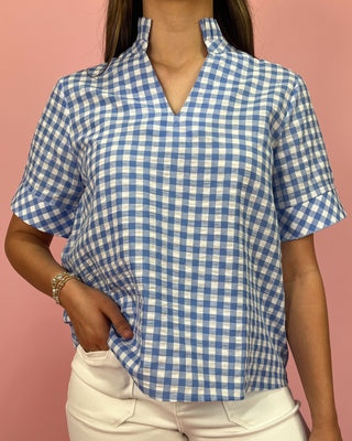 Person wearing a blue and white checkered shirt against a pink background
