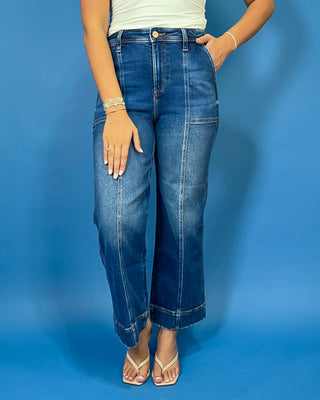 Dark wash high-rise cropped wide leg jeans with contrast front seam detailing, subtle fading, utility-inspired front pockets, and a wide cuffed hem.