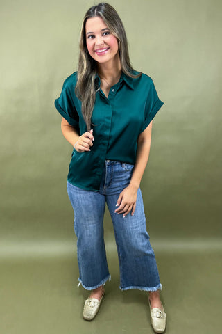Woman wearing a green blouse and blue jeans against a green background