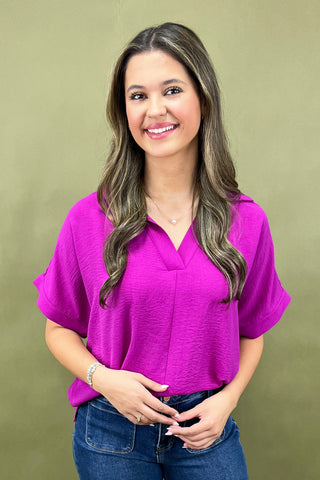 Woman wearing a bright pink blouse against a green background
