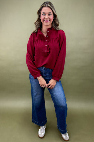 Woman wearing a red blouse and blue jeans against a green background