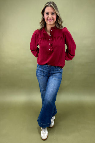 Woman wearing a red blouse and blue jeans against a green background
