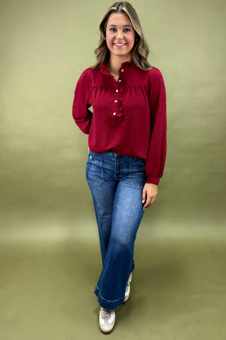 Woman wearing a red blouse and blue jeans against a green background
