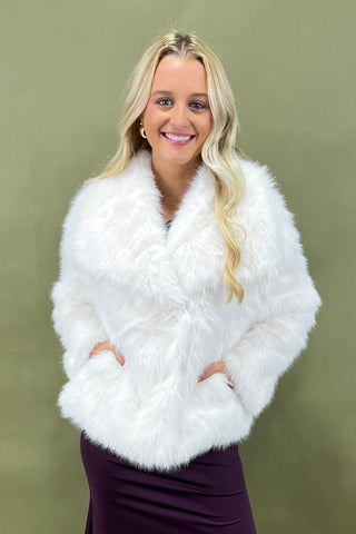 Woman wearing a white feathered shrug against a green background
