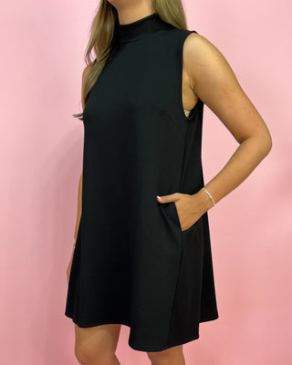 Black sleeveless dress worn by a person on a pink background