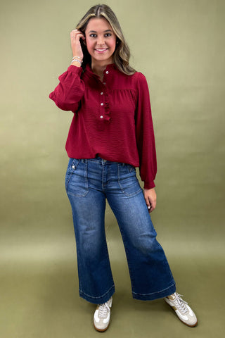 Woman wearing a red blouse and blue jeans against a green background