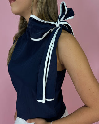 Navy blue top with a large white bow on a pink background