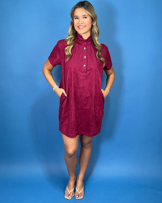 Burgundy suede short sleeve shift dress with a mock neckline, decorative gold button details, and an easy relaxed silhouette.