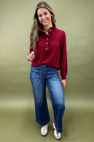 Woman wearing a red blouse and blue jeans against a green background