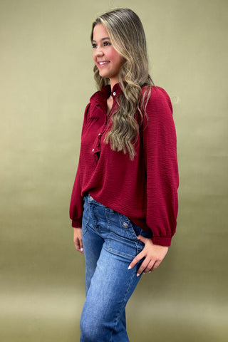Woman wearing a red blouse and blue jeans against a beige background