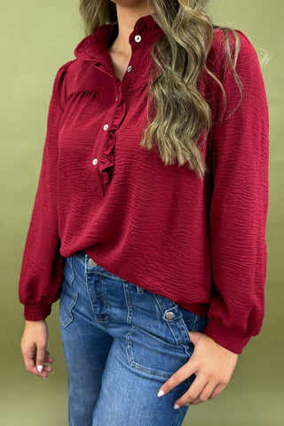 Red long-sleeve top worn by a person on a green background