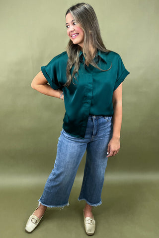 Woman wearing a green blouse and blue jeans against a green background