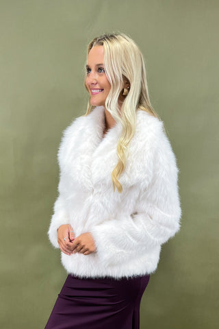 Woman wearing a white fluffy jacket against a green background