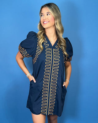 Navy short sleeve shift dress with statement puff sleeves, a flattering V-neckline, contrast tan loop trim detailing, and convenient side pockets.