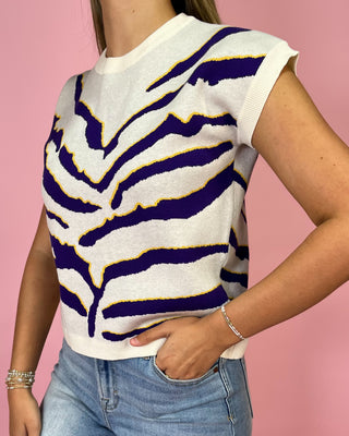 Person wearing a white sleeveless top with purple and yellow zebra pattern against a pink background