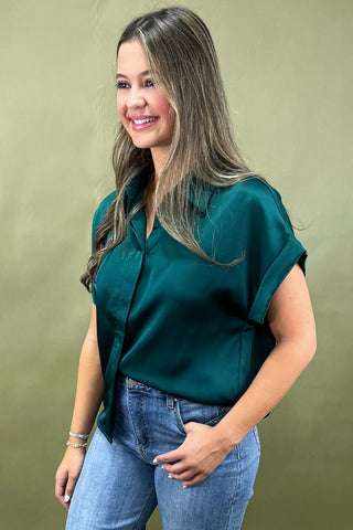 Woman wearing a green blouse and blue jeans against a green background