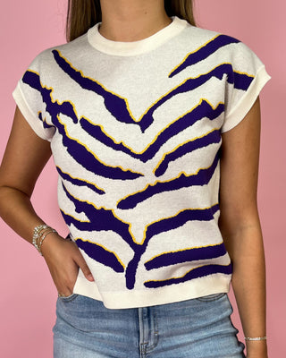 Person wearing a white sweater with purple and yellow zebra pattern on a pink background