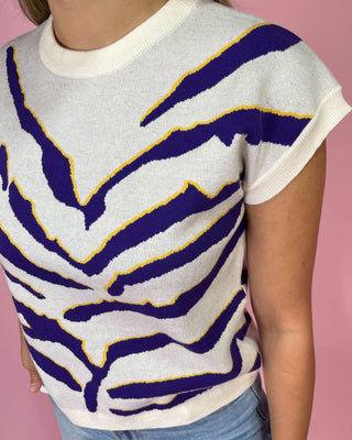 Person wearing a sweater with purple and yellow abstract pattern on a pink background