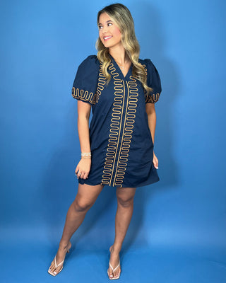 Navy short sleeve shift dress with statement puff sleeves, a flattering V-neckline, contrast tan loop trim detailing, and convenient side pockets.