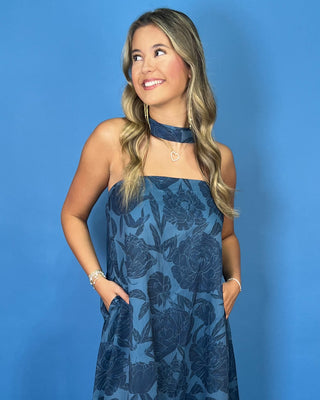 a sleeveless halter-neck maxi dress with a dark blue floral pattern on a medium blue background