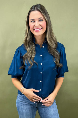 Woman wearing a blue blouse and jeans against a green background