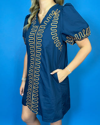 Navy short sleeve shift dress with statement puff sleeves, a flattering V-neckline, contrast tan loop trim detailing, and convenient side pockets.