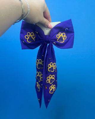 Purple LSU statement hair bow with hand-beaded gold and purple tiger paw prints, rhinestone accents, long tails, and a French barrette clip.