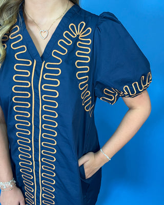 Navy short sleeve shift dress with statement puff sleeves, a flattering V-neckline, contrast tan loop trim detailing, and convenient side pockets.