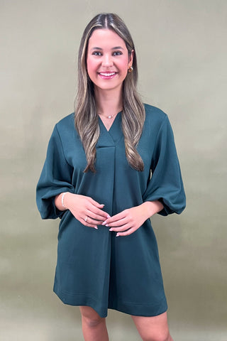 Woman wearing a teal dress against a green background