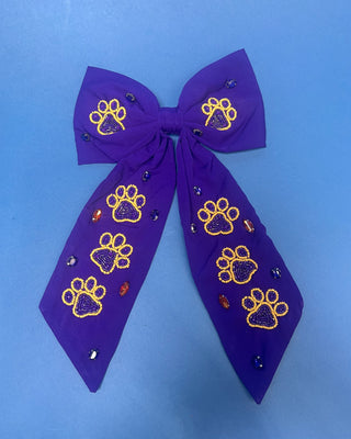 Purple LSU statement hair bow with hand-beaded gold and purple tiger paw prints, rhinestone accents, long tails, and a French barrette clip.
